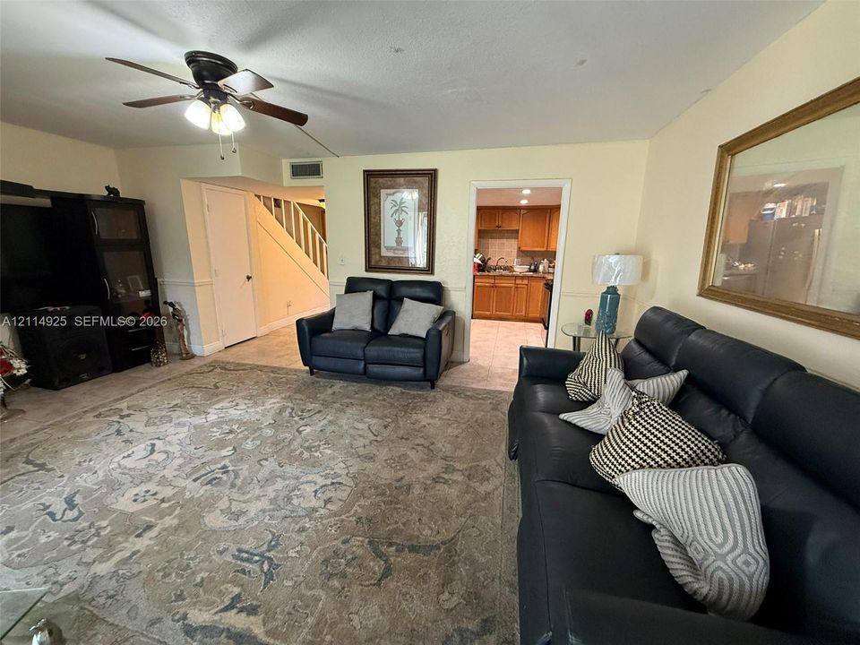 Living area featuring ceramic tile flooring, a multi-blade ceiling fan with integrated lighting, and chair rail molding