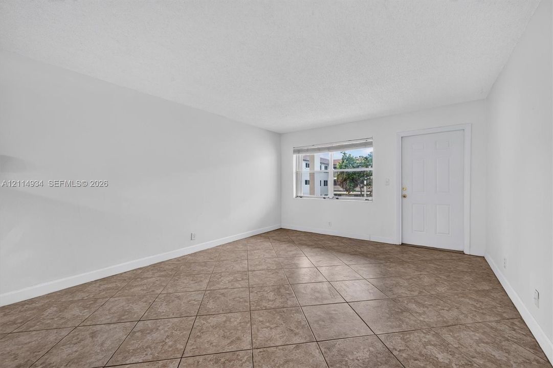 Neutral-toned room featuring diagonal-set tile flooring, white walls, and a recessed window with horizontal blinds