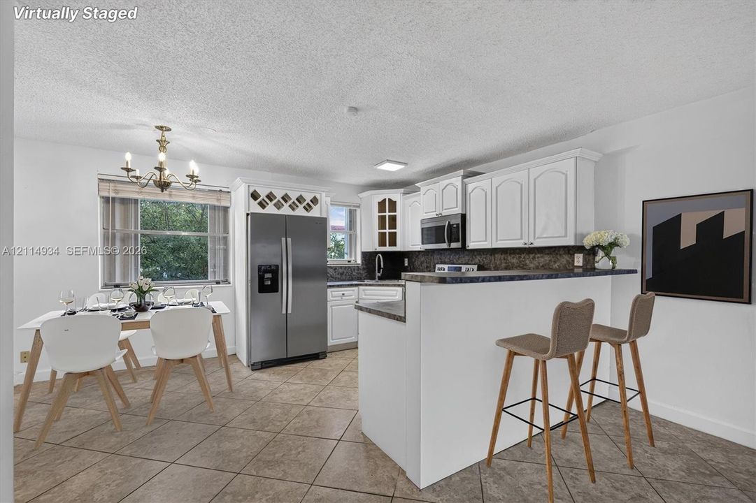 Kitchen featuring white cabinetry, stone-finish countertops, stainless steel appliances, built-in wine storage, and ceramic tile flooring