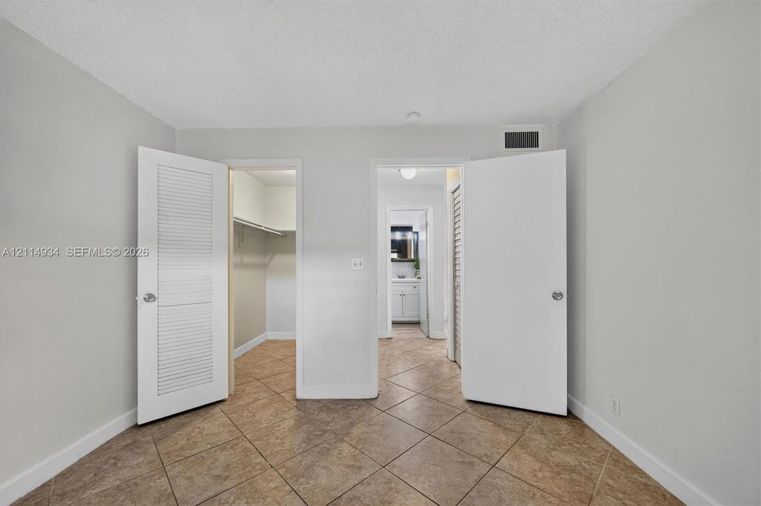 Tile flooring, neutral wall tones, and dual louvered-style closet doors