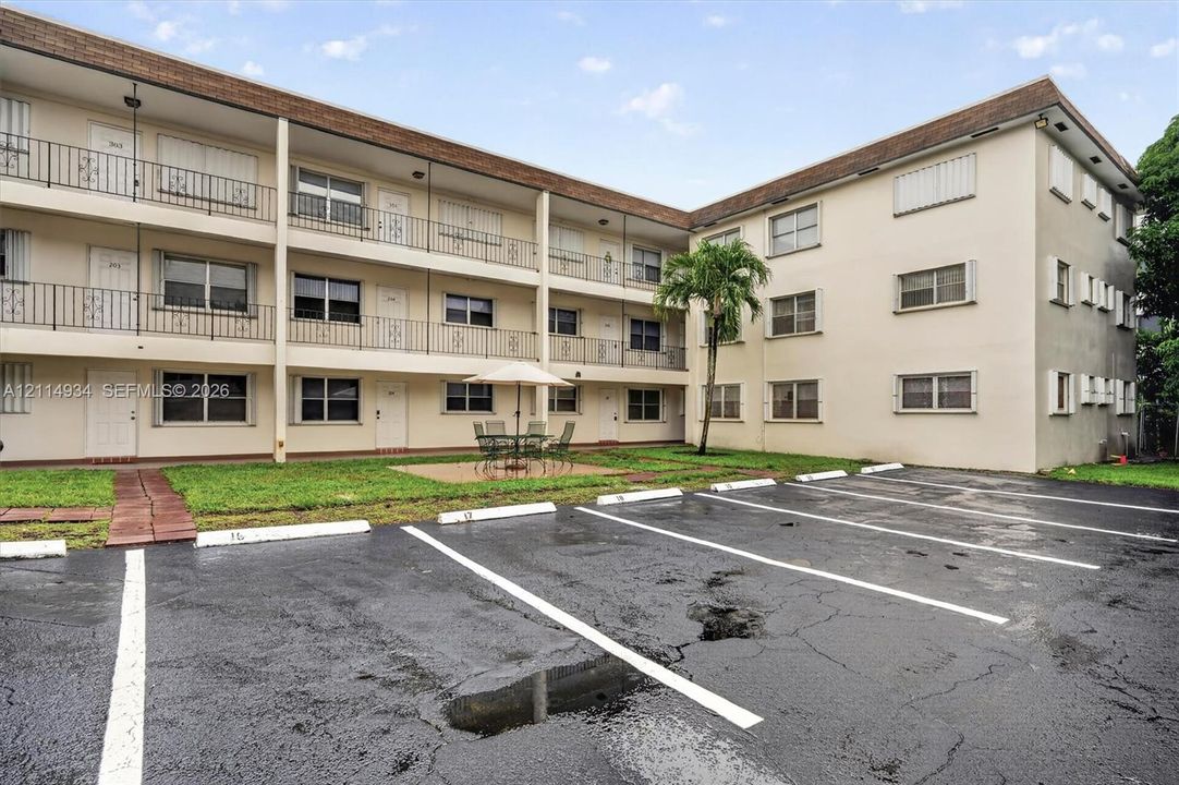 Multi-story exterior featuring a stucco facade, private balconies with decorative metal railings, and dedicated on-site parking spaces
