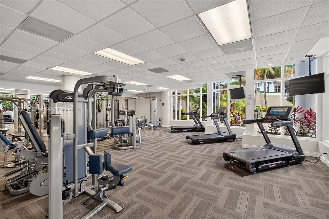 Fitness center featuring expansive floor-to-ceiling windows, high-contrast patterned carpeting, and recessed lighting