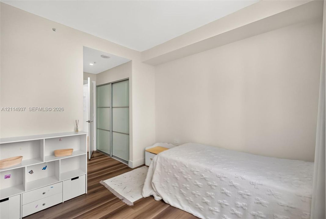 Interior space featuring wood-finish flooring, sliding glass-panel closet doors, and recessed ceiling lighting