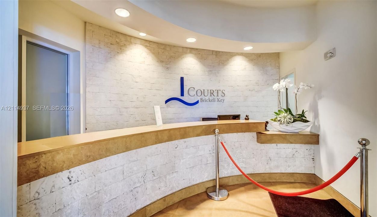 Reception area featuring a curved stone-clad desk, textured stone wall finish, recessed ceiling lighting, and custom signage