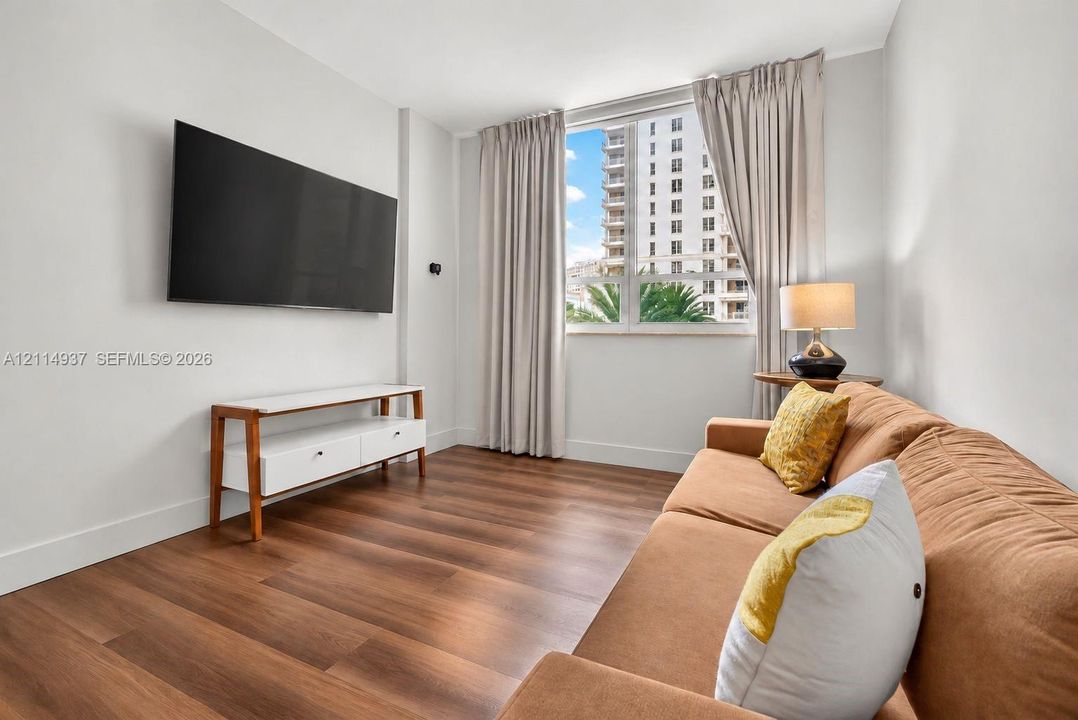 Room featuring wood-finish flooring, a large window, and neutral wall paint
