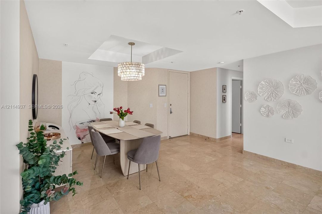 Polished stone flooring, recessed ceiling lighting, tiered crystal chandelier, and neutral wall tones