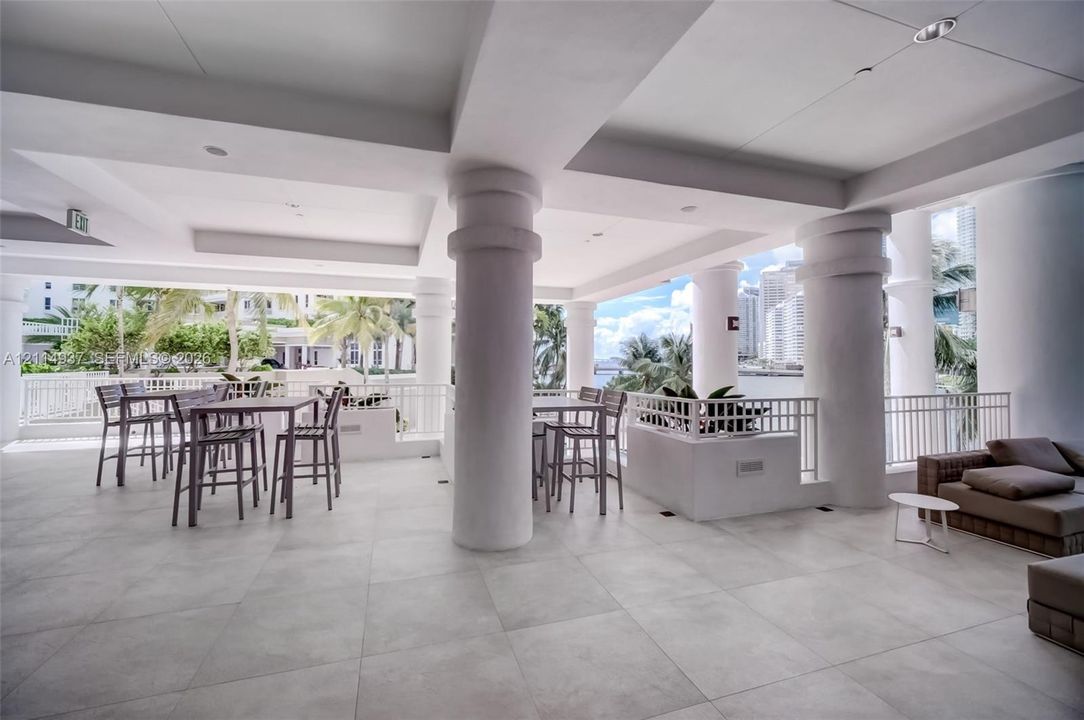 Covered terrace featuring large-format stone-style tile flooring, structural columns, and white metal railing