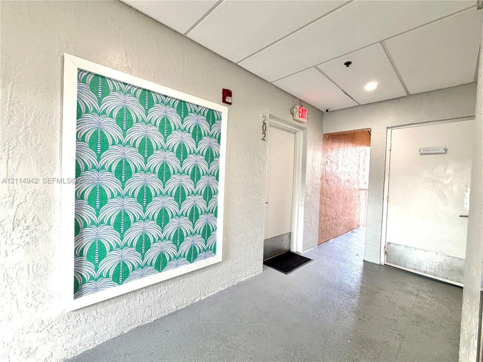 Textured wall finish, framed decorative wall panel, smooth-finish concrete flooring, and solid-core metal entry doors