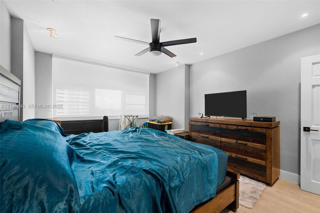 Room featuring wood-finish flooring, a matte black ceiling fan, recessed lighting, and a white interior door with matte black hardware