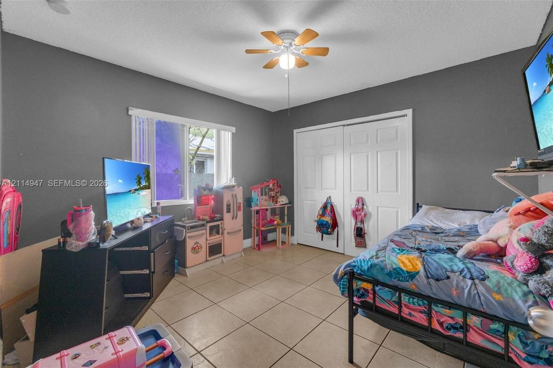 Room featuring neutral-toned walls, tile flooring, a six-panel closet door, and a ceiling fan with integrated lighting