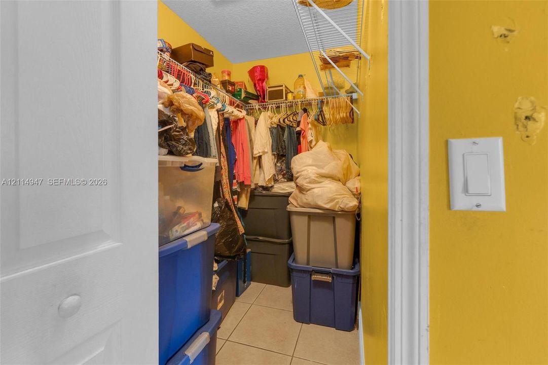 Walk-in storage space featuring ceramic tile flooring, wire shelving, and a single-pole light switch