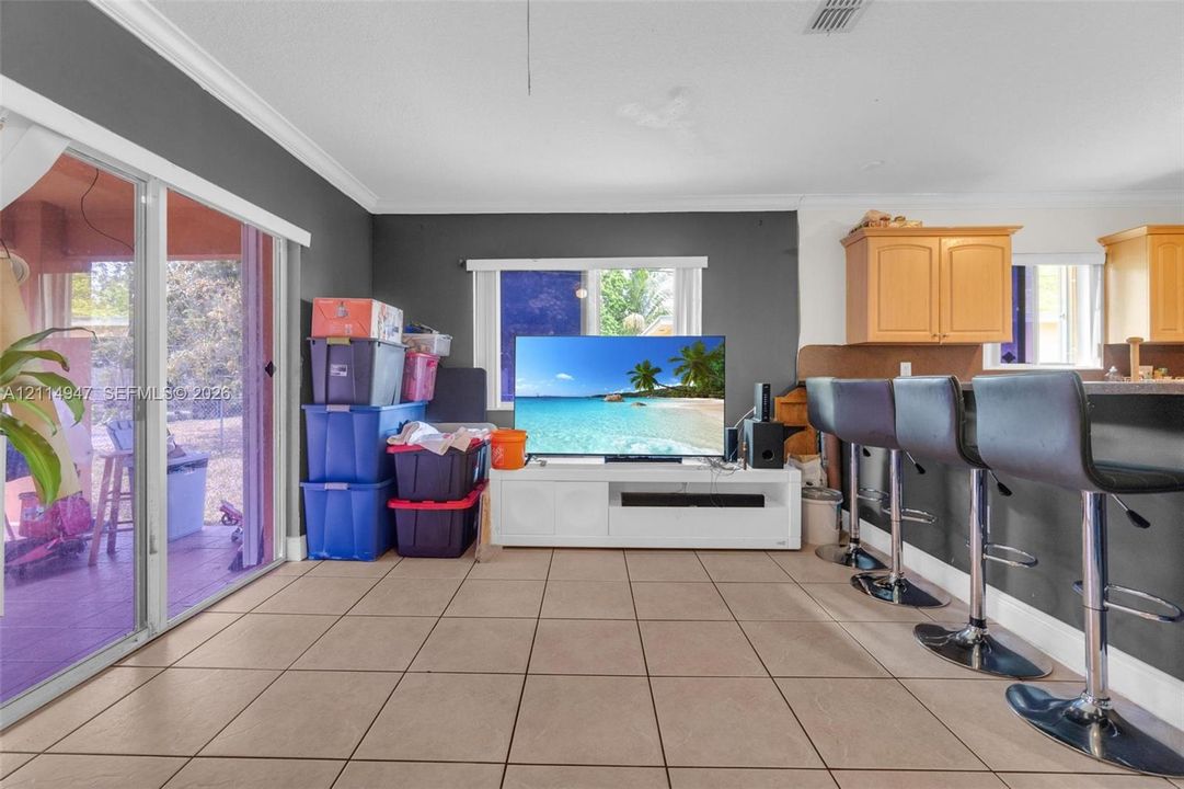 Large-format floor tile, crown molding, and sliding glass patio doors, featuring a kitchen island with built-in cabinetry