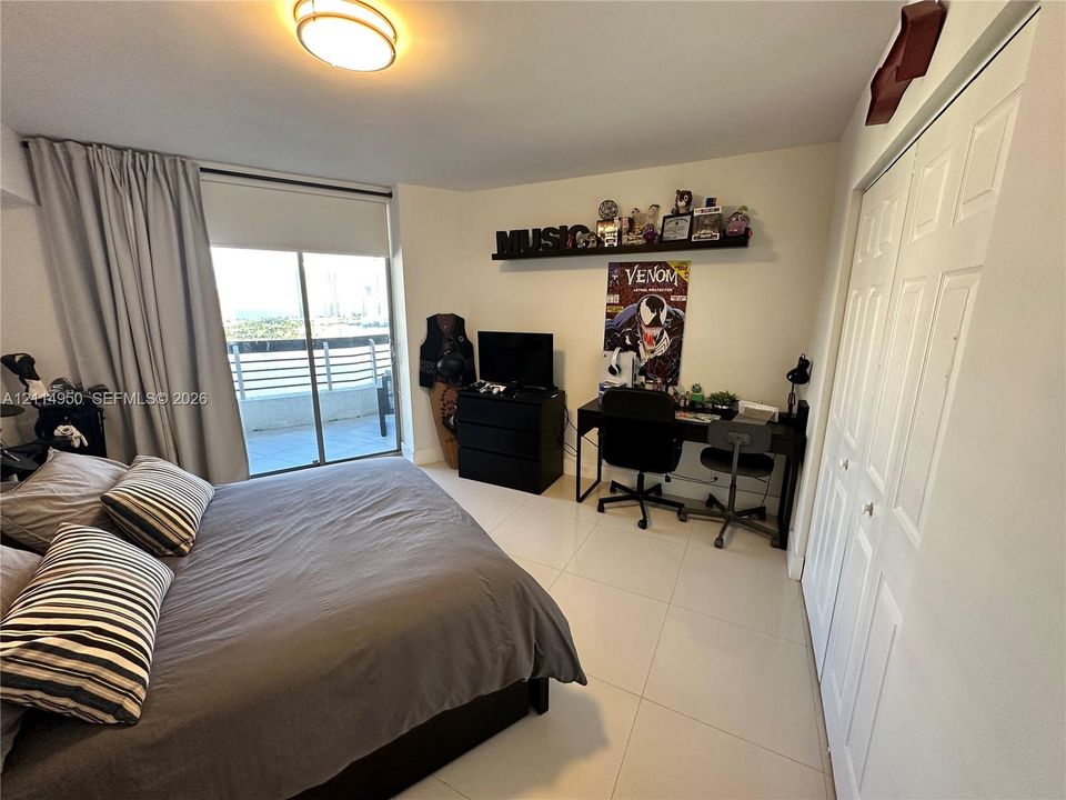 Spacious room featuring large-format tile flooring, a sliding glass door with balcony access, and double-panel closet doors