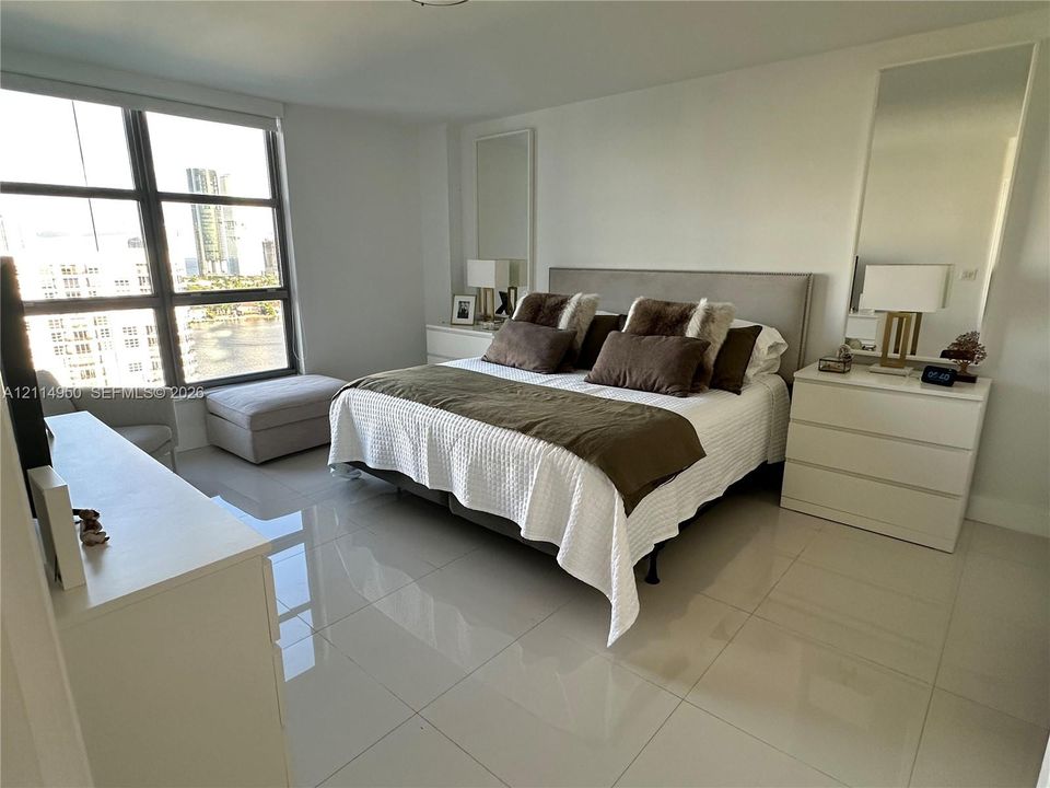 Floor-to-ceiling windows with grid-patterned framing, large-format polished tile flooring, and integrated wall mirrors