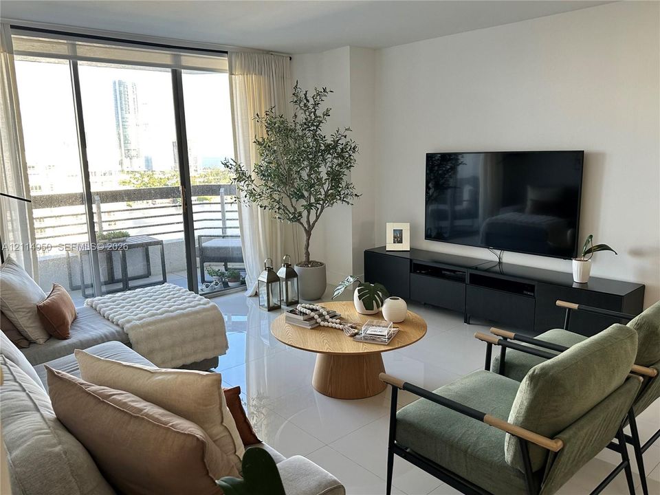 Living area featuring floor-to-ceiling glass sliding doors, private balcony, and polished tile flooring