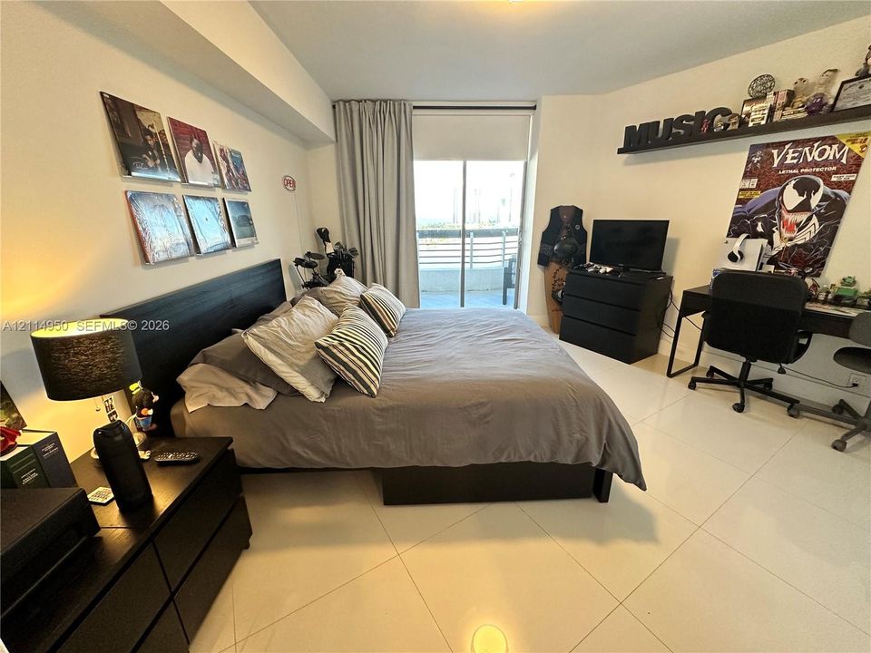 Spacious room featuring glossy tile flooring, neutral wall tones, and floor-to-ceiling glass sliding doors opening to a private balcony
