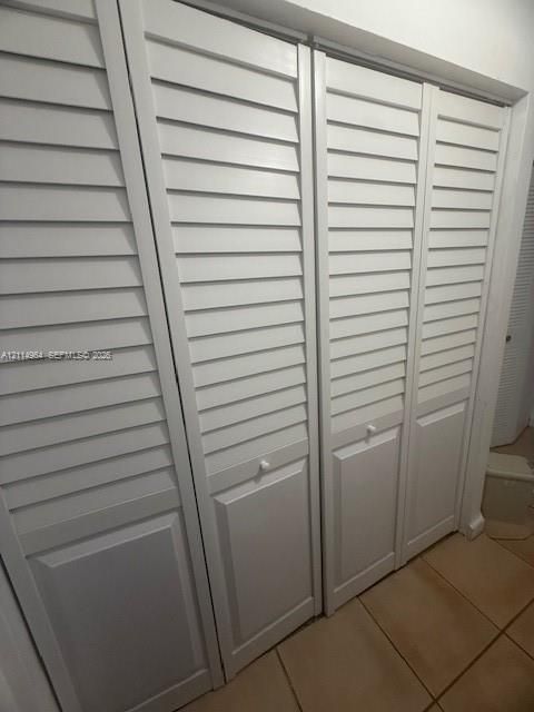 Double closet featuring white bifold louvered doors and ceramic tile flooring