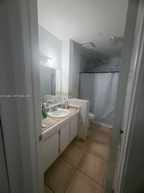 Bathroom featuring a tile countertop vanity with an integrated basin, tile flooring, and a tub-shower combination with decorative wall tile surround