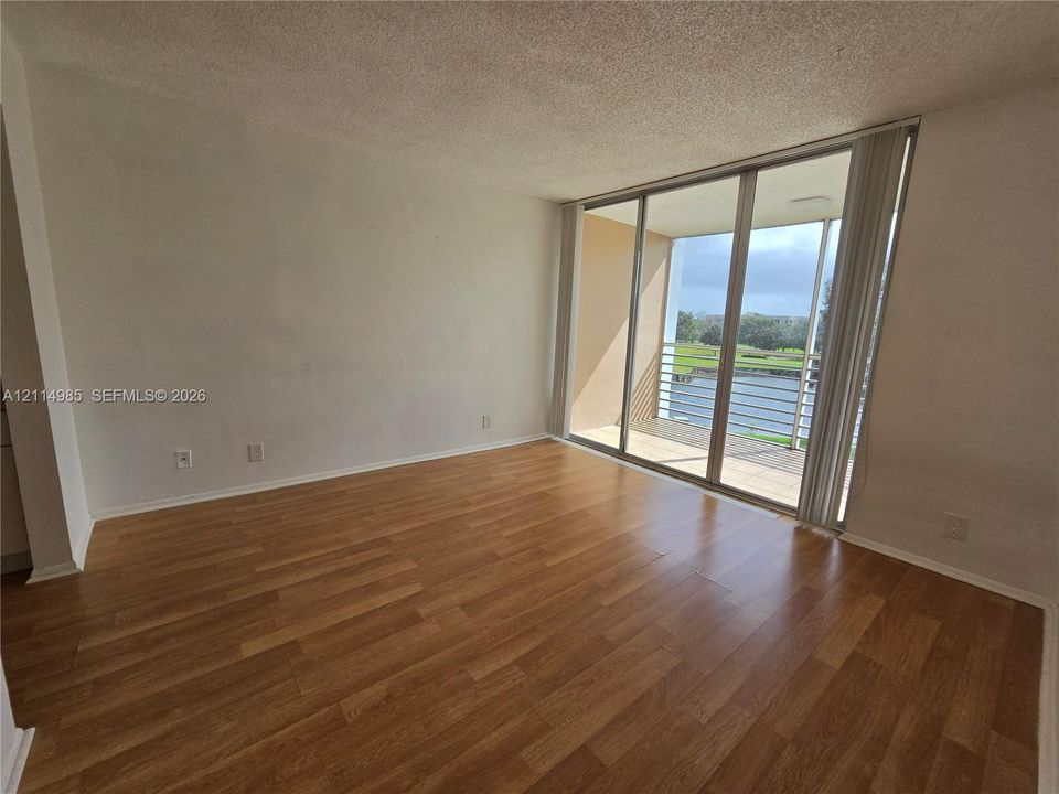 Wood-finish flooring, sliding glass patio doors, and a covered balcony overlooking a water feature