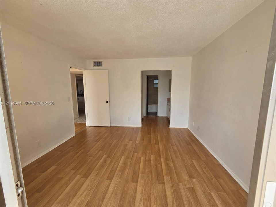 Interior room featuring wood-finish flooring, neutral wall paint, and multiple interior doorways
