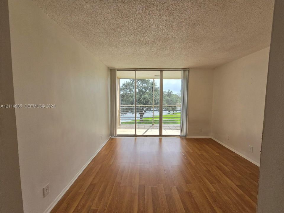Interior space featuring wood-finish flooring, textured ceiling, and floor-to-ceiling sliding glass doors opening to an exterior balcony