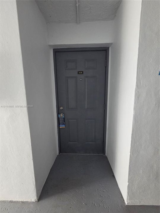 Six-panel entry door featuring a matte finish, a deadbolt lock, and a centered peephole