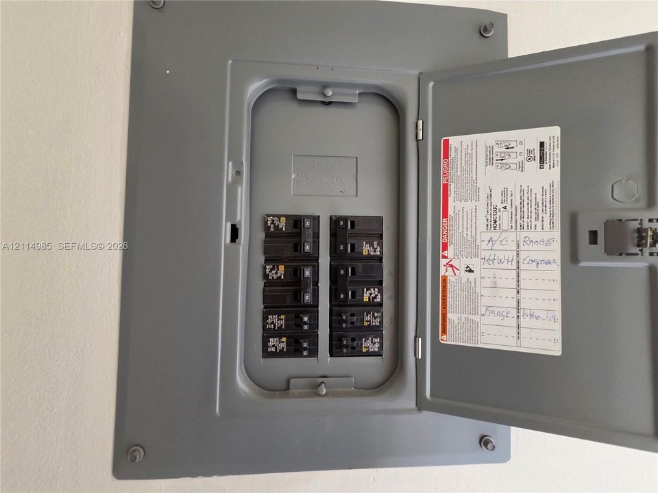 Electrical panel featuring a gray metal enclosure with a hinged door and multiple circuit breakers