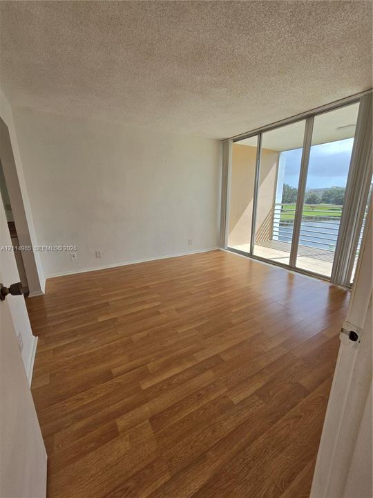 Wood-finish flooring, full-height sliding glass doors, and an outdoor balcony with metal railing