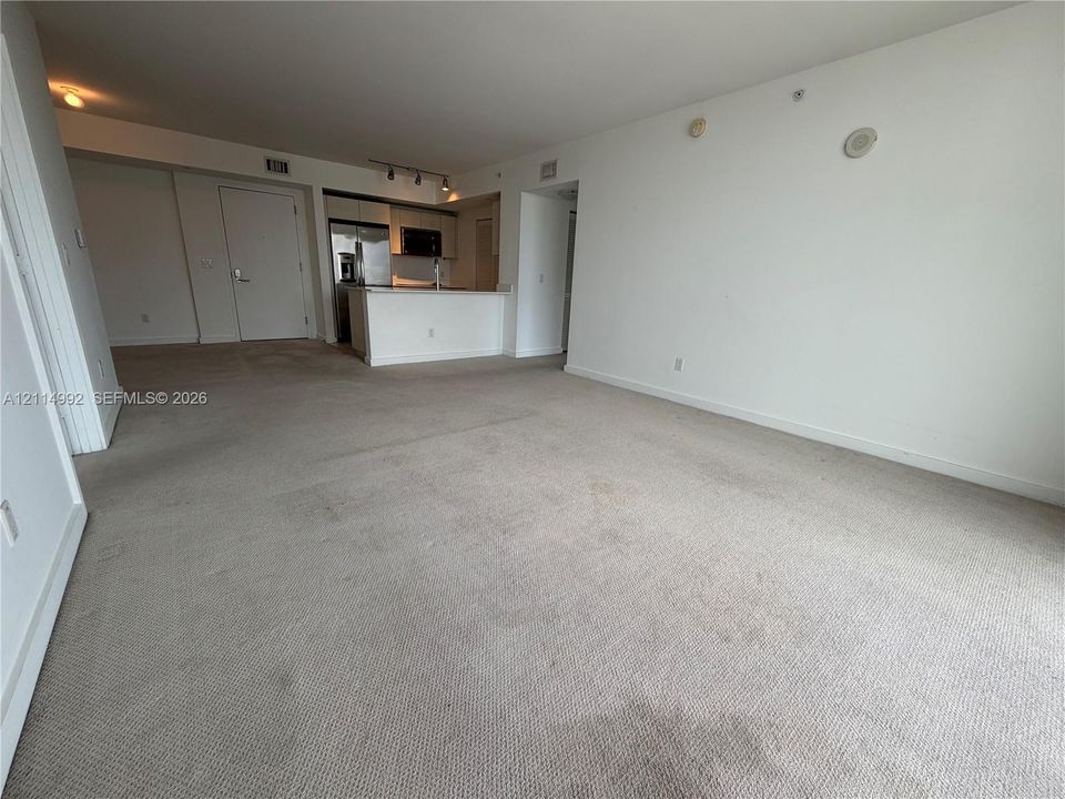 Open-concept interior featuring neutral wall-to-wall carpeting and a kitchen with built-in cabinetry and a peninsula counter