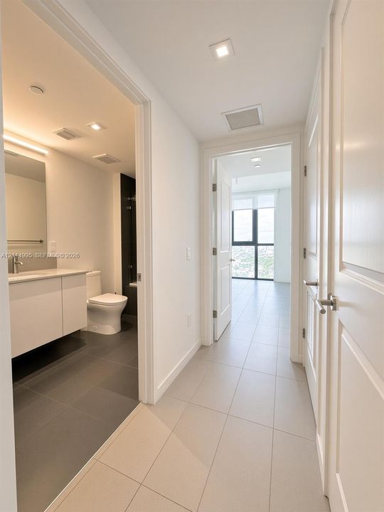 Hallway featuring neutral large-format tile flooring, recessed lighting, and white paneled doors