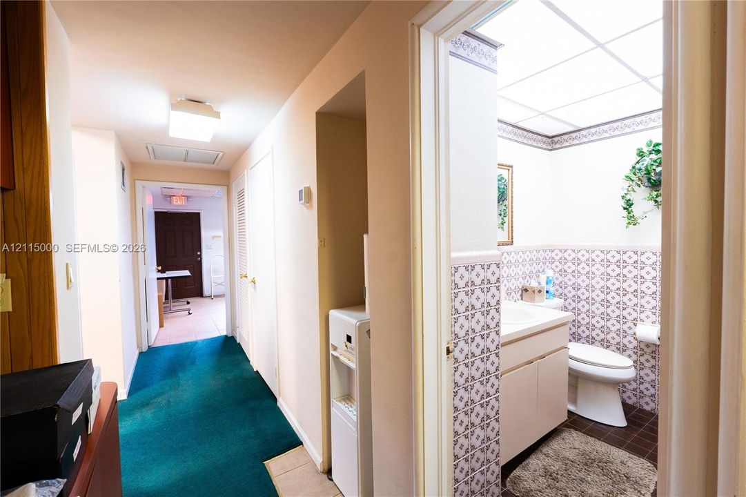 Bathroom featuring decorative tile wainscoting, a drop-in vanity sink, a recessed drop-ceiling light fixture, and floor-level tile surfacing