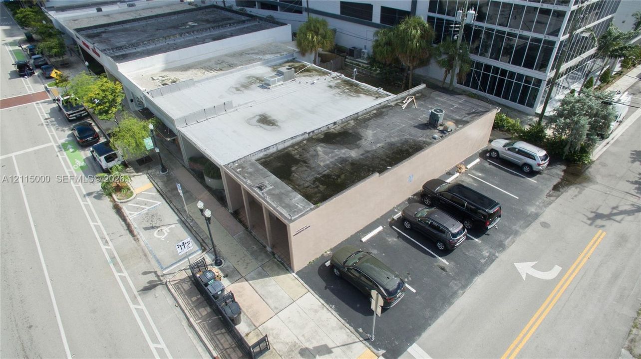 Corner commercial building featuring a flat roofline, exterior stucco finish, and dedicated on-site parking area