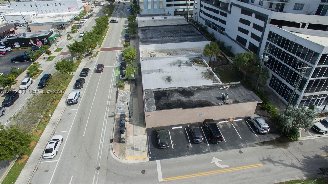 Corner lot commercial building featuring a paved surface parking area, flat roofing, and exterior masonry walls