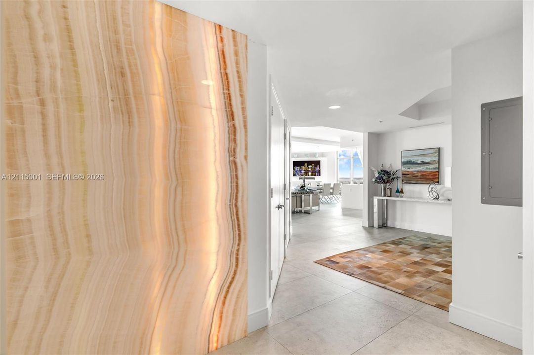 Large-scale natural stone feature wall with prominent veining and light-toned tile flooring throughout the interior