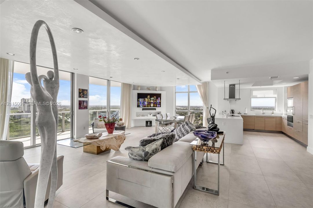Open-concept interior featuring large-format tile flooring, recessed ceiling lighting, floor-to-ceiling glass windows, and a built-in entertainment niche