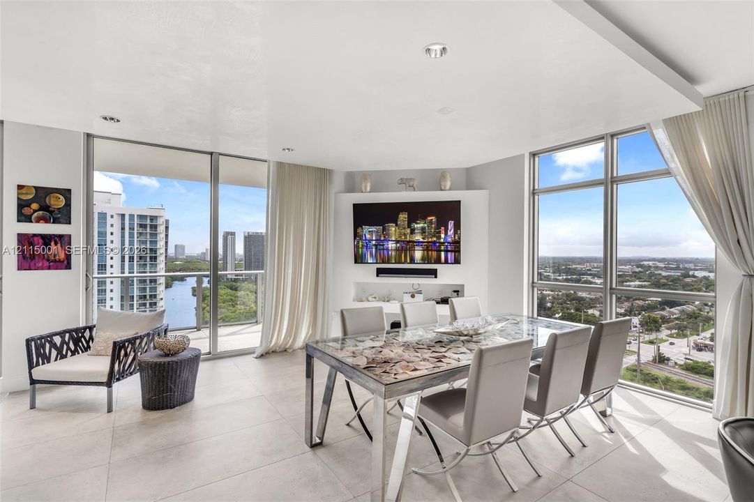 Open-concept living space featuring floor-to-ceiling windows, large-format tile flooring, a recessed ceiling panel with integrated lighting, and a custom built-in media console