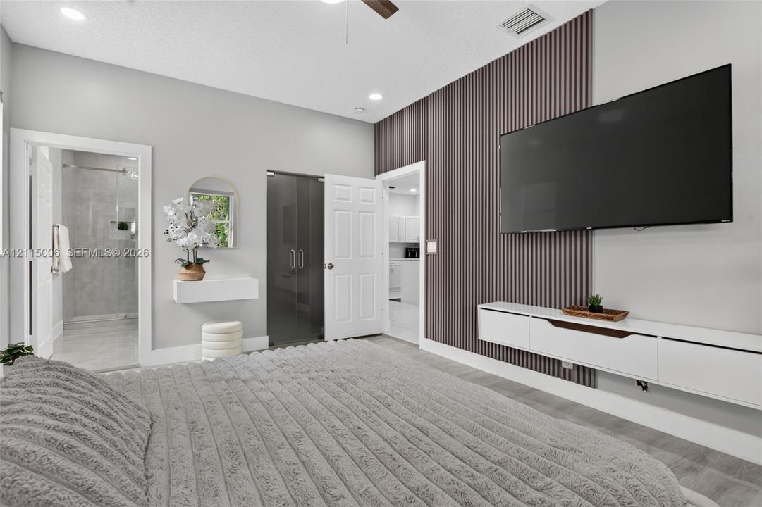 Vertical slat wood-finish accent wall, wall-mounted white media console, recessed ceiling lighting, ceiling fan, and floating wall shelf
