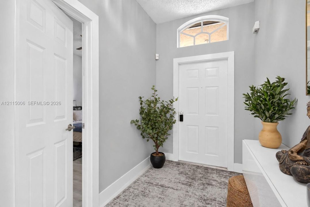 Entryway featuring a white paneled door, arched transom window, and neutral wall color