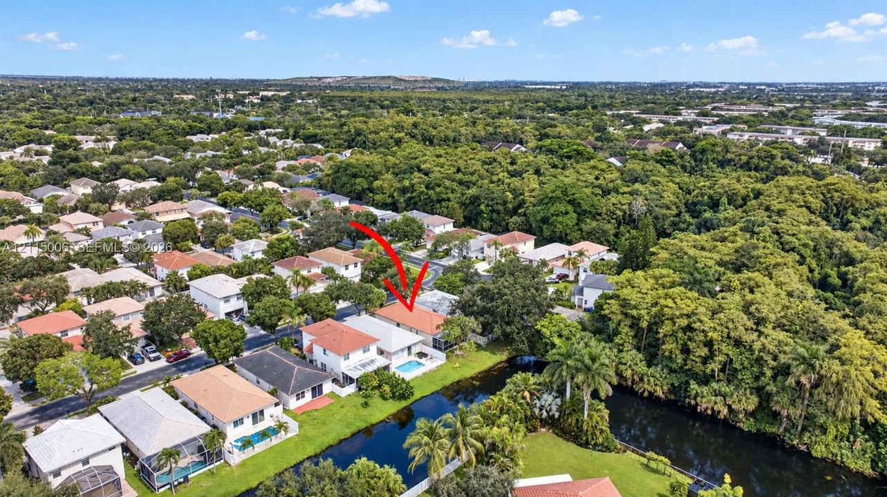 Aerial perspective of a multi-story residence featuring a tile roof, an in-ground swimming pool, and a waterfront location