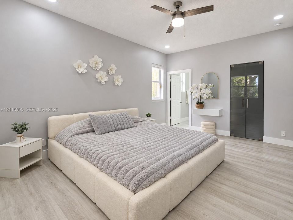 Neutral interior featuring wood-finish flooring, recessed lighting, a modern ceiling fan, and dark-tinted glass panel doors