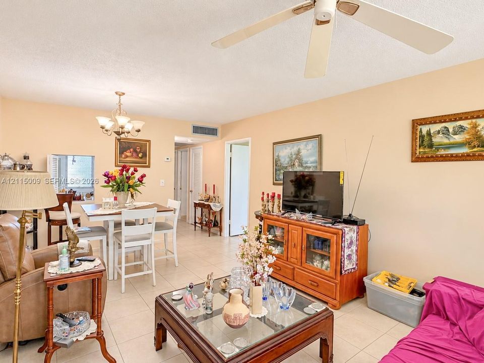 Open-concept interior featuring light-toned tile flooring, a multi-arm ceiling chandelier, and a white ceiling fan