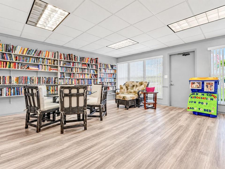 Spacious room featuring floor-to-ceiling built-in shelving, wood-finish flooring, recessed lighting, and expansive windows with vertical blinds