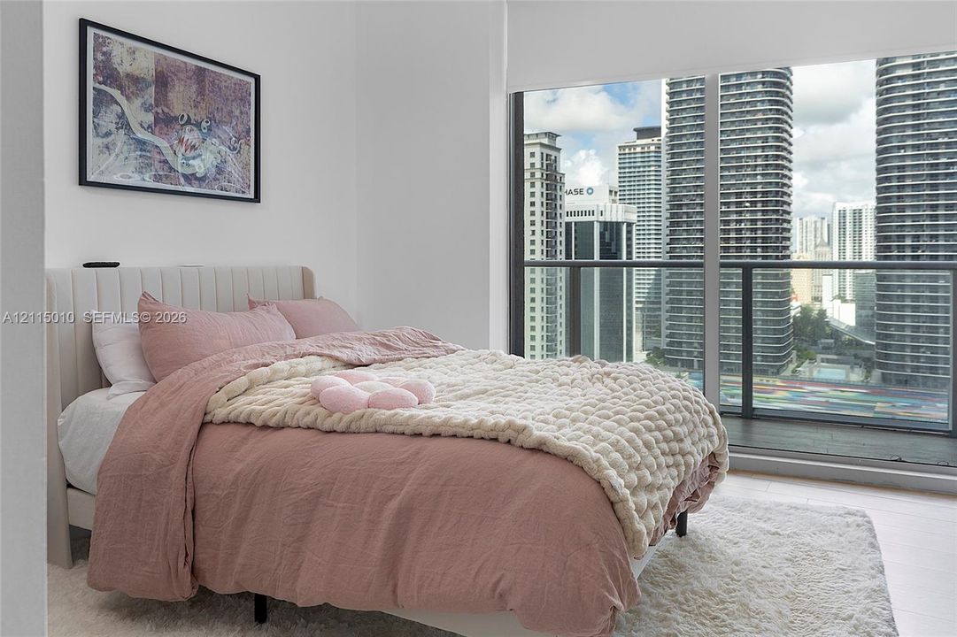 Floor-to-ceiling windows featuring urban skyline exposure, integrated balcony access with dark-framed railing, and light-toned hard-surface flooring