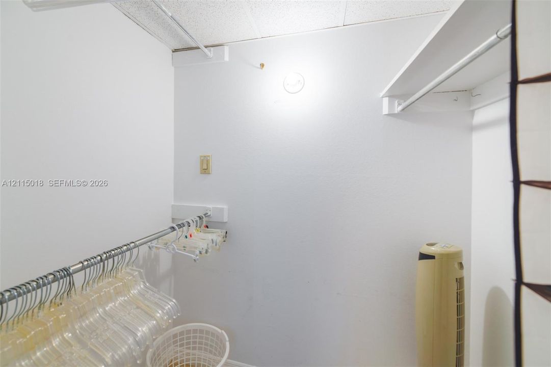 Walk-in closet featuring multi-level metal garment rods and built-in white shelving