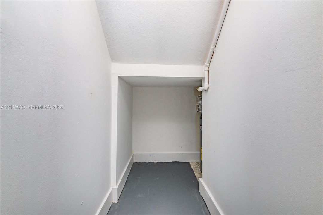Enclosed alcove featuring painted wall surfaces, angled ceiling, and solid-surface flooring