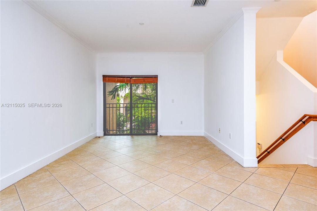 Neutral-toned ceramic tile flooring, sliding glass doors with dark metal frames, and a wooden handrail