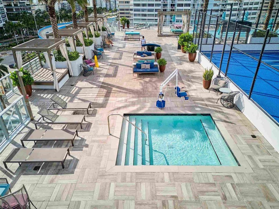 Rooftop terrace featuring a tiled deck, built-in swimming spa, court area, and multiple shaded cabanas