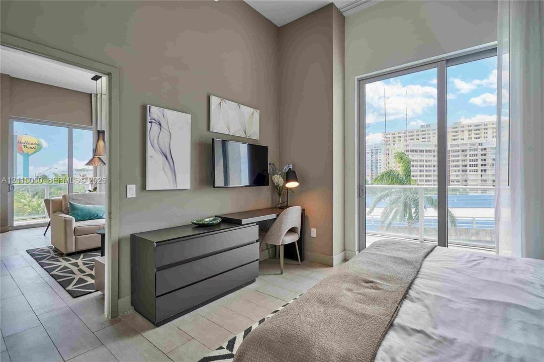 Floor-to-ceiling sliding glass doors, neutral ceramic tile flooring, and a private balcony with glass railing