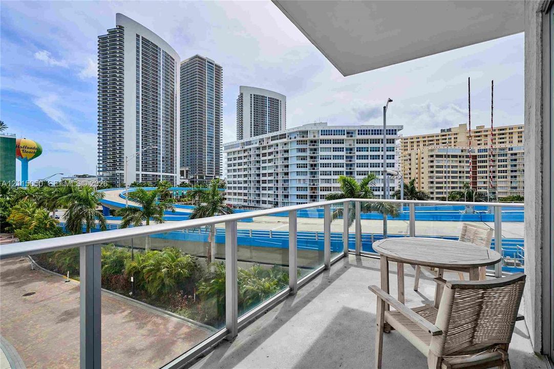 Private balcony featuring a concrete floor and a transparent glass railing with a metal frame