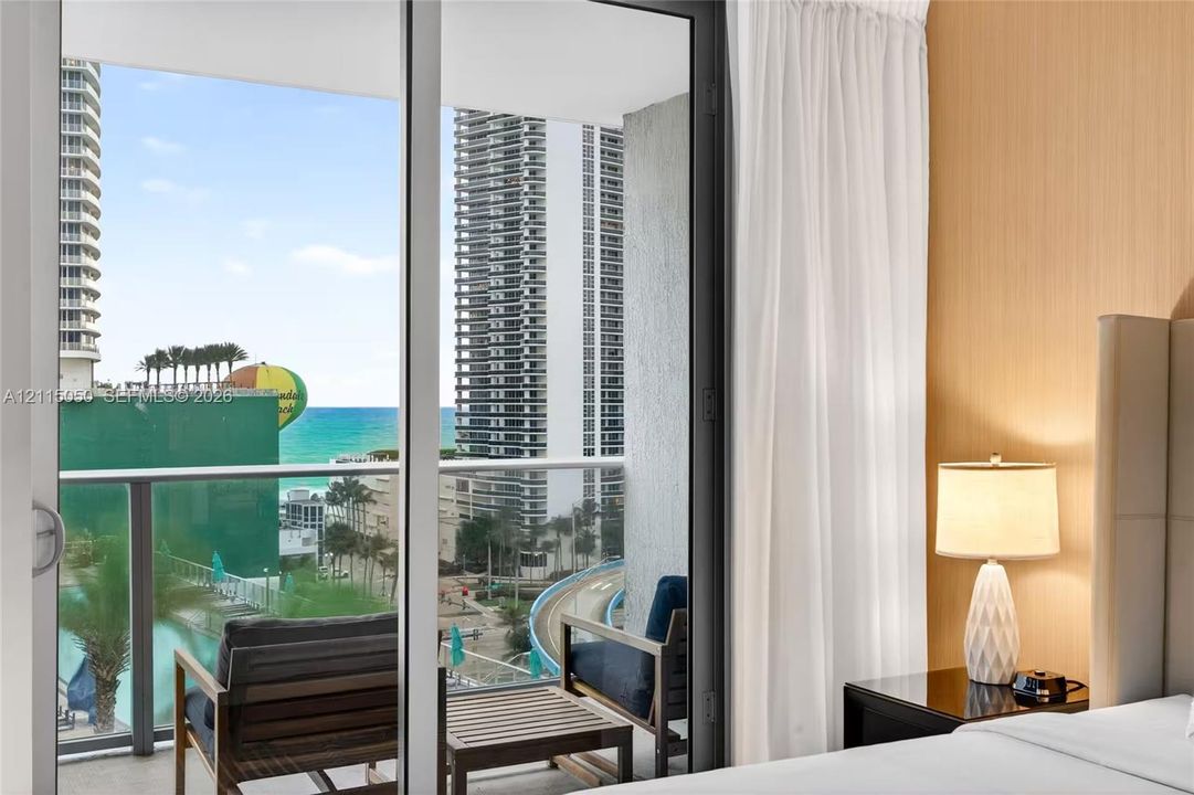 Floor-to-ceiling glass sliding doors opening to a private balcony featuring a glass railing and outdoor flooring